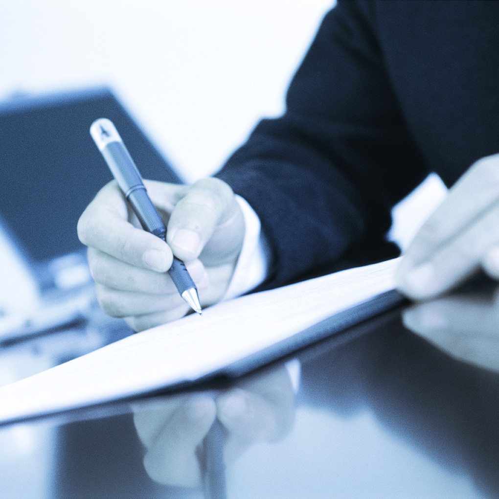 Businessman signing document at desk, close-up of hands